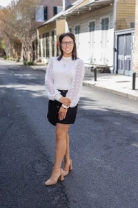 Harley smiling in white blouse and black skirt standing on street